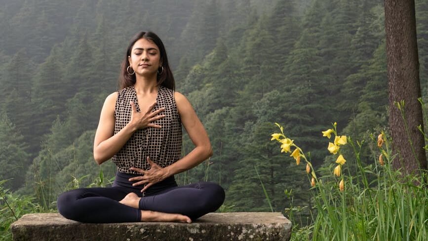 woman sitting on bench in forest and exercising yoga