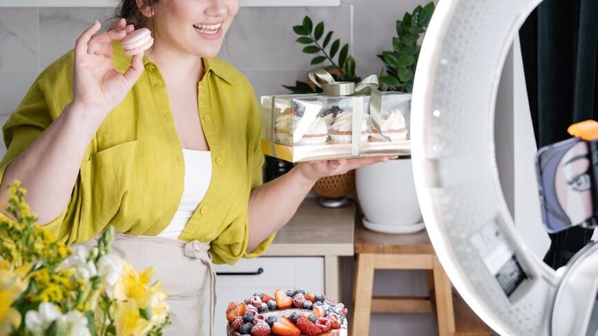 smiling woman showing assorted yummy homemade cakes while recording vlog