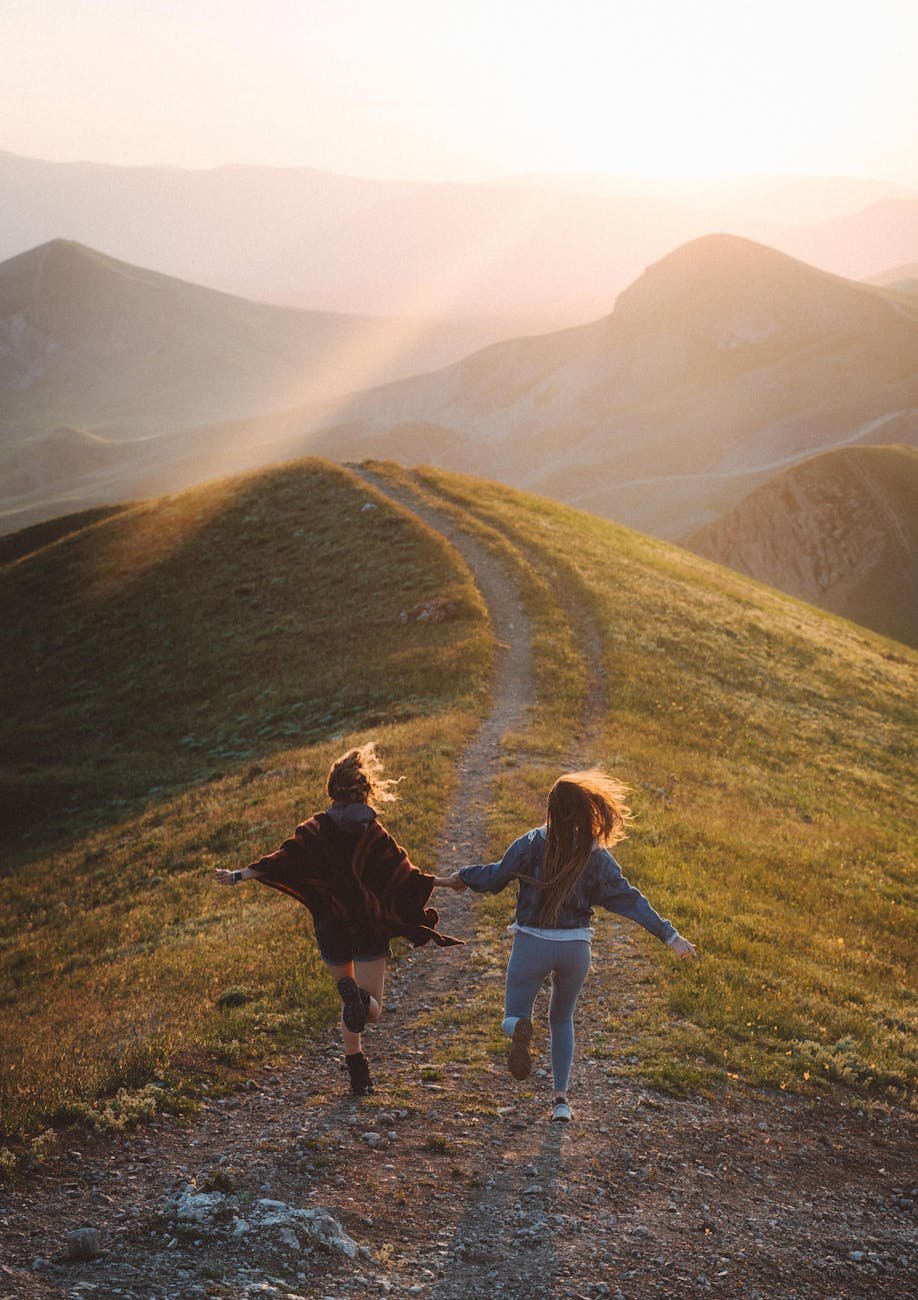 women running on the mountain trail during sunset